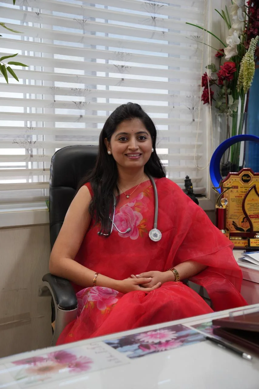 Real photograph of Dr Mayuri Avhad-Wagh in her clinic wearing a red sari and stethoscope