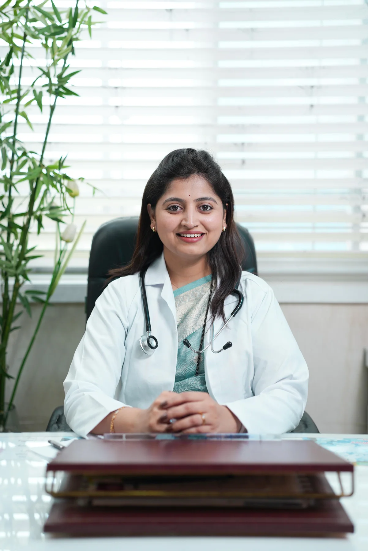 Real photograph of Dr Mayuri Avhad-Wagh at her clinic desk in a white coat